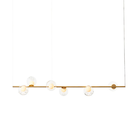 Slim brass linear chandelier with six clear globe lights